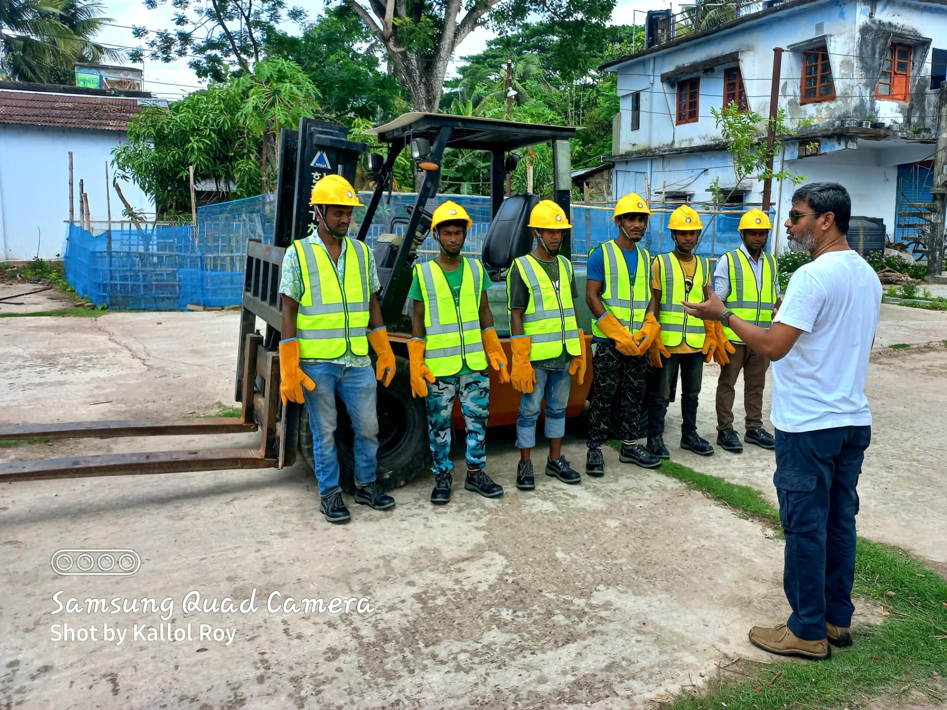 MYM Corporation site team in safety gear briefed beside a forklift during a JICA project operation